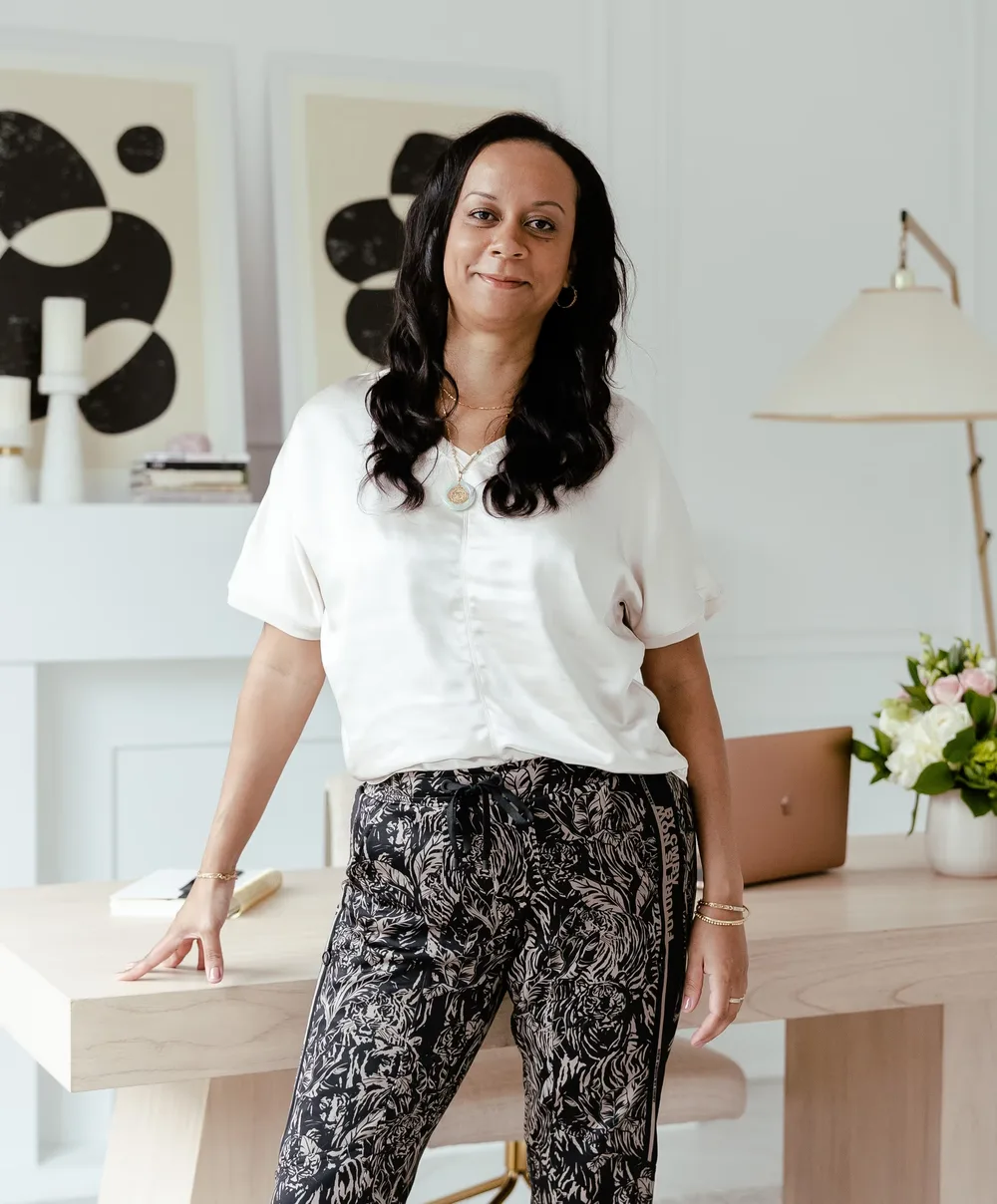Gabrielle Thomas leaning on her desk in her studio